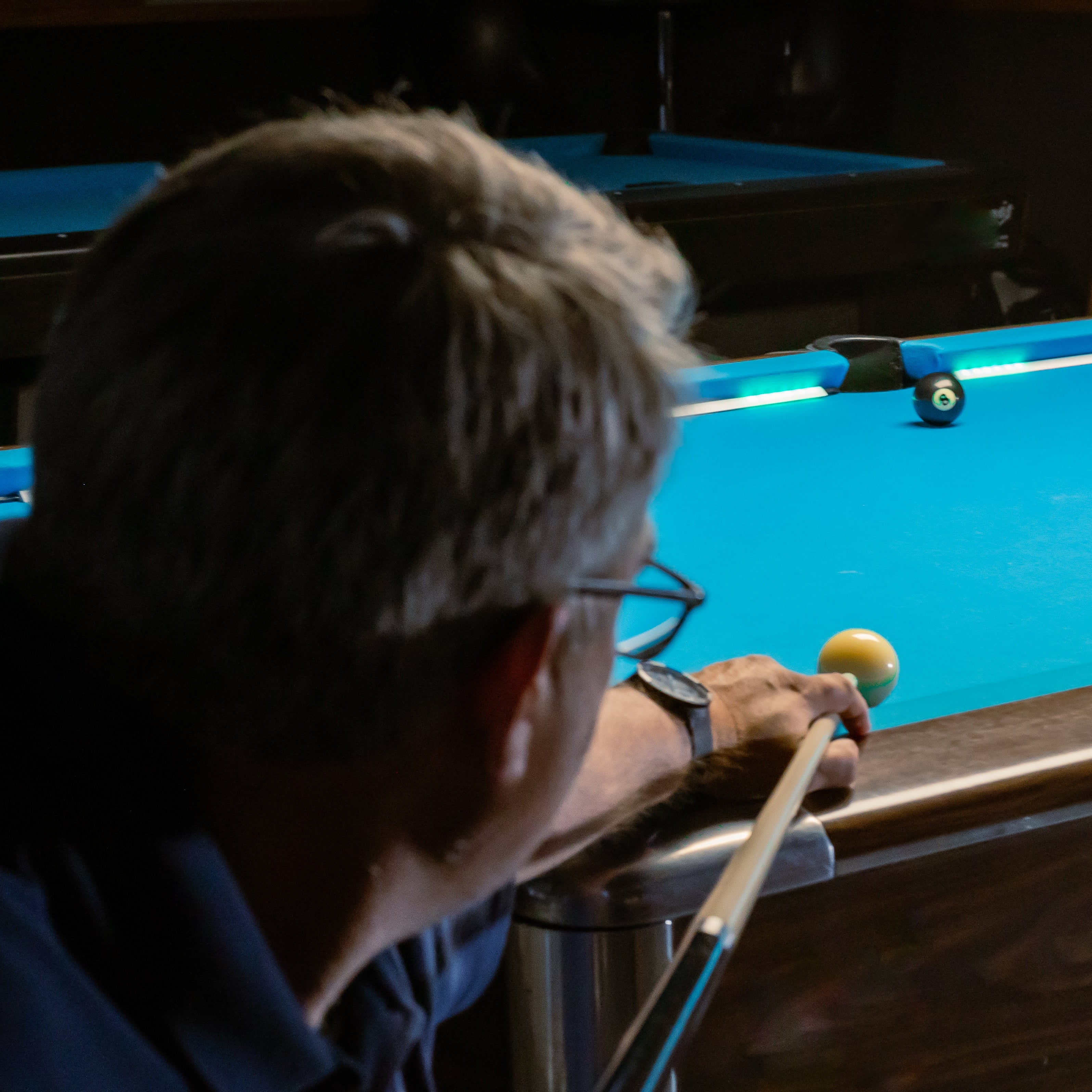 Person playing pool, focusing on the cue ball and the lights